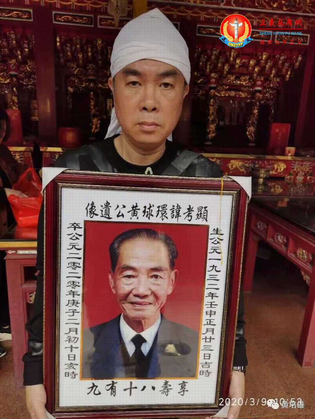 黄培雄抱着父亲黄环球的遗像.png